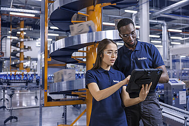A male and a female Leadec employee looking at a tablet and monitoring the production of cleaning agents.