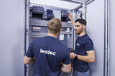 Zwei Leadec-Mitarbeiter bei der Überprüfung eines Schaltschranks.