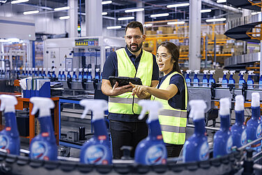 A male and a female Leadec employee looking at a tablet and monitoring the production of cleaning agents.