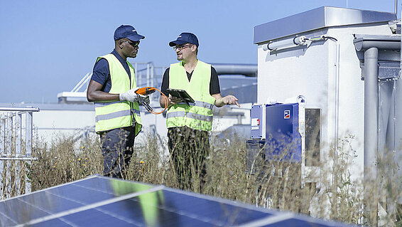 Two Leadec employees on factory roof with photovoltaic panels.